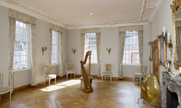 Heller und größter Raum im Roten Haus mit einer reich verzierten Stuckdecke und einen mit Einlegarbeiten verzierter Parkettboden. In der Mitte steht eine Harfe mit einem Hocker.